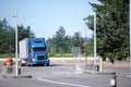 Blue modern semi truck with trailer running to rest area entrance with green trees Royalty Free Stock Photo