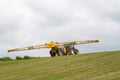 Blue modern tractor pulling a crop sprayer on hill