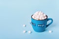 Blue monday concept. Blue mug of cocoa with marshmallows on blue background. Mug is decorated with eyelashes down