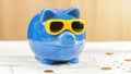 Blue money box of pig form with sunglasses stands on table Royalty Free Stock Photo