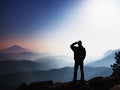 Blue morning. Hiker is standing on the peak of rock in rock empires park and watching over misty landscape.