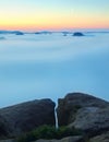 Blue morning, view over rock and fresh green trees to deep valley full of light mist. Dreamy spring landscape within daybreak Royalty Free Stock Photo