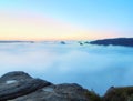 Blue morning, view over rock to deep valley full of light mist. Dreamy spring landscape within daybreak Royalty Free Stock Photo