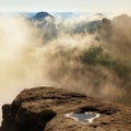 Blue morning, view over rock to deep valley full of light mist. Dreamy spring landscape within daybreak Royalty Free Stock Photo