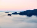 Blue morning, view over rock to deep valley full of light mist. Dreamy spring landscape within daybreak Royalty Free Stock Photo