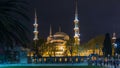 Blue Mosque on night timelapse view from lawn with palm in Istanbul.