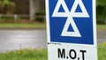 Blue MOT service sign on british road on cloudy rainy day