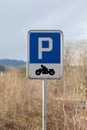 Blue motorbike parking sign with black motorbike and white writing with large P on blue background