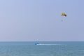 blue motorboat on horizon in Andaman Sea rolls man under parachute, shallow DOF,copy space.