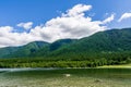Blue mountain lake with green mountains blue sky and white clouds