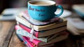 A blue mug with best teacher ever text on a stack of books on a wooden surface in a blurred background Royalty Free Stock Photo