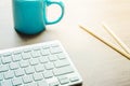 Blue mug with coffee tea white computer keyboard pencils on wood desk. Designer copywriter student freelancer blogger workplace