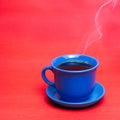 Blue mug with steaming hot coffee. Soft smoke. Red background. Royalty Free Stock Photo