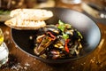 Blue mussels in white wine sauce in black bowl. Delicious healthy seafood closeup served on a table for lunch in modern