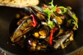 Blue mussels in white wine sauce in black bowl. Delicious healthy seafood closeup served on a table for lunch in modern