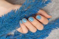 Blue nail design. Manicured female hand on gray background