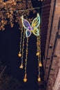 A blue neon butterfly glows against a background of a dark sky at dusk