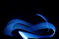 Blue neon curved wave of light as curls, swirl or spiral with dotted stripes on black background, pattern. Royalty Free Stock Photo