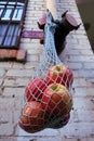 Blue net bag with yellow and red apples hanging from a white brick wall Royalty Free Stock Photo