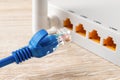 Blue network cable plug almost inserted into the yellow socket of white wi-fi wireless router. Wlan router for home and office for Royalty Free Stock Photo