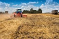 Blue new tractor pulls a red harrow in the field