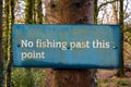 Blue no fishing past this point sign on a tree in a woodland beside the water Royalty Free Stock Photo