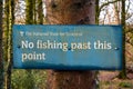 Blue no fishing past this point sign on a tree in a woodland beside the water Royalty Free Stock Photo