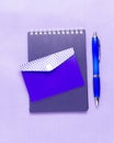 Blue Notepad and blue pen on a purple background. Monochrome. Royalty Free Stock Photo