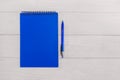 Blue notepad and blue pen on a white wooden background. Copy space. Place for your text Royalty Free Stock Photo