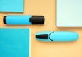 Blue notepads and markers on an orange surface. Top view of office supply