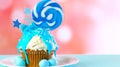 Blue novelty cupcake decorated with candy and large lollipops.