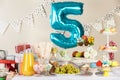 Blue number five balloon over table with delicious treats at Birthday party