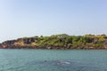 Blue ocean on the background of a rocky coast with bright green vegetation under a clear blue sky view from the sea Royalty Free Stock Photo