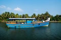 Blue ocean fishing boat along the canal Kerala backwaters shore with palm trees between Alappuzha and Kollam, India Royalty Free Stock Photo