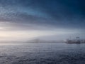 Blue ocean surface and sky, Galway city town and port in a fog. Nature scene with calm relaxing mood