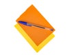 Blue office pen on blank orange and yellow layered note pad pages isolated over white. Top down view Royalty Free Stock Photo