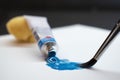 Blue oil paint, tube and brush on white paper Royalty Free Stock Photo