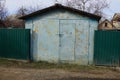 Blue old iron garage and part of a green metal fence Royalty Free Stock Photo