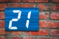 Blue metallic sign on red brick wall with digit 21