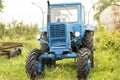 blue old MTZ 53 tractor on orchard, simple mechanical technology agricultural vehicle