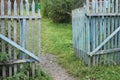 A blue old ragged gate to a dacha garden in a village with ground and grass and trees Royalty Free Stock Photo