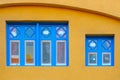 Blue old style wooden windows, symmetry in open doors, yellow house wall background in small town, minimal style of simplicity, Royalty Free Stock Photo