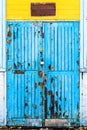 Blue old wooden door with peeling paint and big damages, doorway in a yellow white abandoned building Royalty Free Stock Photo