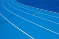 Blue Olympic track lanes with white stripes, an empty background suitable for copy space, represent the concept of physical sports