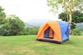 Orange color family camping tent with ground sheet setup on green park campsite