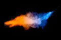 Blue orange color powder explosion cloud on black background. Closeup of Blue orange dust particles splash Royalty Free Stock Photo