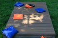 Blue and orange cornhole bags on a board during a backyard game Royalty Free Stock Photo