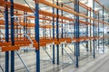 Blue and orange empty warehouse shelves in grey industrial interior