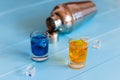 Blue and orange shots near metal sheker on wooden