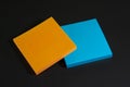 Blue and orange stickers lie on a black matte surface. Stationery on a black table Royalty Free Stock Photo